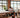 Person working at a long table in a modern office with large windows.